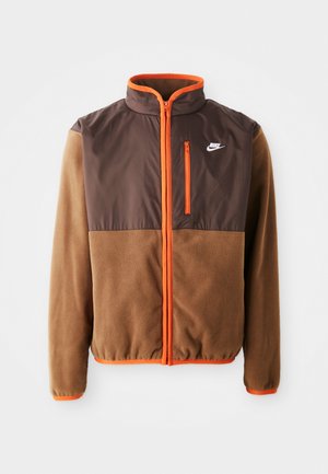Nike jakna s tijelom od smešnog flisa i tamnosmešnim gornjim delom, narančastim akcentima, visokim ovratnikom i džepom na grudima sa patentnim zatvaračem.