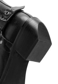 Zwarte leren laars met een rechthoekige, gestructureerde hak, voorzien van een band met metalen hardware en drukkers aan de zijkant.
