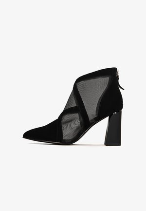 Schwarze Knöchelstiefel aus einer Kombination von Wildleder und Mesh-Materialien, mit spitzer Schuhspitze und Blockabsatz. Reißverschlussverschluss hinten.