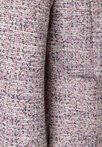 Gewebter Stoff mit einer Mischung aus rosa, blauen und schwarzen Fäden sowie einem strukturierten Muster. Enthält ein dezentes Taschendetail.