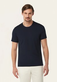 Marineblauwe katoenen t-shirt met een ronde halslijn en korte mouwen. Aansluitend ontwerp, gladde textuur, minimale details. Draagt met lichtgekleurde broeken.