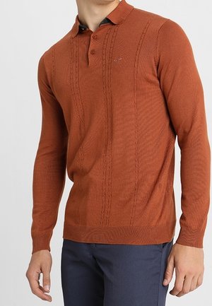 Rdzawoczerwona koszulka polo z długim rękawem, z teksturowanym wzorem z przodu i kontrastowym kołnierzykiem. Wykonana z miękkiego, prążkowanego materiału.