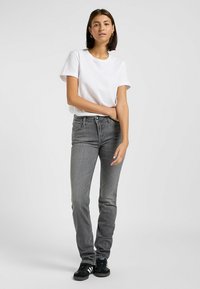 Grijze jeans met een slim fit en subtiele vervaging, gecombineerd met een effen wit t-shirt met ronde hals en zwarte sneakers. Eenvoudig ontwerp, minimale accenten.