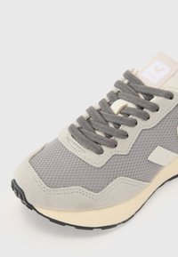 Light gray mesh and suede sneaker with round toe, textured upper, gray laces, and cream sole. Includes branded logo on tongue.