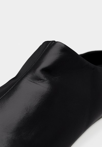 Μαύρο γυαλιστερό δερμάτινο μοκασίνι με λεία, αρμονική σχεδίαση και διακριτικό ράψιμο στο πάνω άκρο.