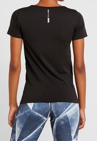 Svart kortärmad sporttröja med rund halsringning. Har en logotypdetalj på baksidan. Slät textur och åtsittande design.