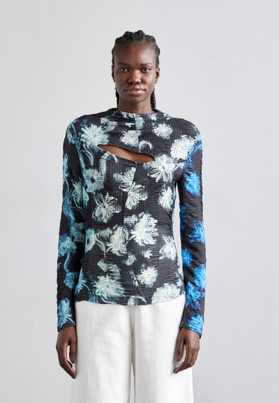 Svart blomsterbluse med blå og hvite mønstre, med et utskjæringsdetalj og teksturert stoff, lange ermer og en tettsittende design.