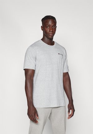 Gray cotton t-shirt with short sleeves, crew neck, and a small logo on the left chest. The model wears light gray sweatpants.