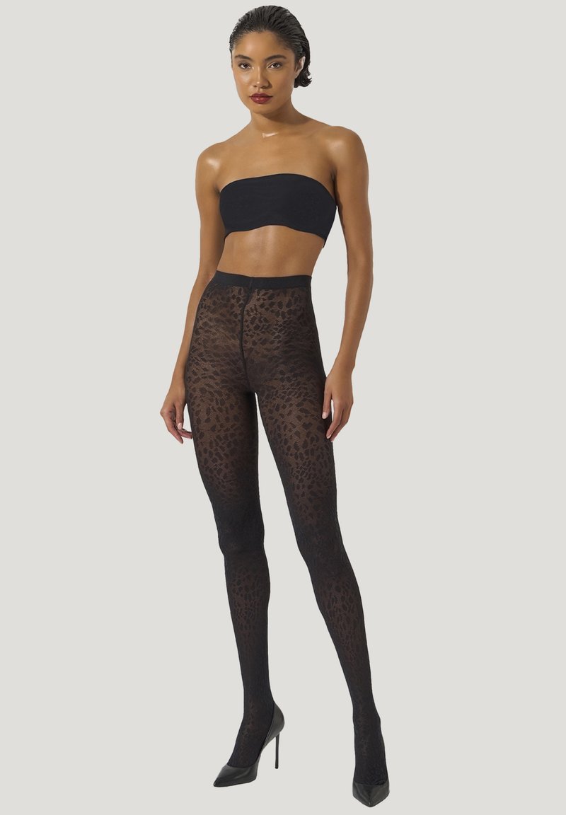 Svarta leopardmönstrade strumpbyxor i genomskinligt material med hög midja, i kombination med en svart bandeau-topp och stilettklackar.