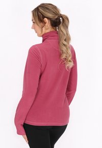 Fleece pullover in roze, met een hoge kraag, lange mouwen en een gladde textuur. Ontworpen met platte naden voor extra comfort.