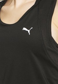 Camiseta sin mangas deportiva negra hecha de una tela suave y elástica. Presenta un cuello redondo y un logo de puma saltando en blanco en el lado izquierdo del pecho.