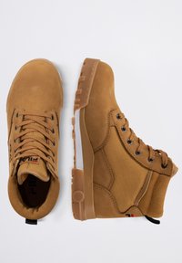 Bottes chelsea brunes avec une tige en cuir texturé et en toile, lacets ronds, semelle en caoutchouc renforcée et un détail de logo sur le côté.