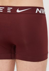 Maroone boxershorts lavet af strækstof, med et hvidt Nike-logo på taljebåndet og et glat, sømløst design.