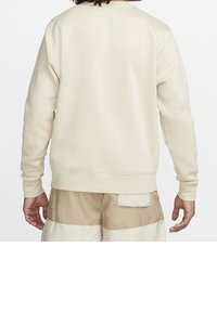 Ljusbeige sweatshirt med rundad hals, långa ärmar och ribbade muddar och nederkant. Slät textur, enkel design, inga synliga logotyper eller mönster.