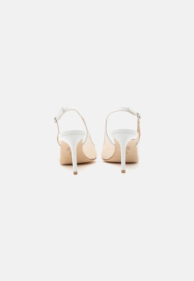 Paire de chaussures à talons hauts slingback blanches avec bouts pointus, texture en dentelle détaillée, et brides réglables à la cheville, vue de dos.