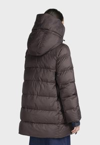 Giacca a vento imbottita marrone scuro con cappuccio, caratterizzata da un design trapuntato e cuciture orizzontali. Texture liscia con una finitura leggermente lucida.