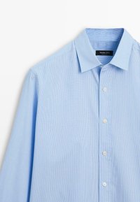 Světle modrá košile s dlouhými rukávy vyrobená z bavlny, s límcem na knoflíky, předními knoflíky a jemnými vertikálními pruhy.