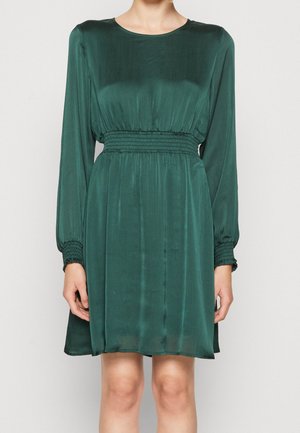 Green satin dress with long sleeves, smocked waist, and a relaxed fit. Features a round neckline and subtle vertical pleats.