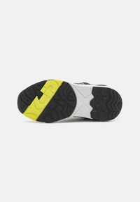Sneaker sole with black rubber, yellow and gray accents. Tread pattern features deep grooves for traction and stability.