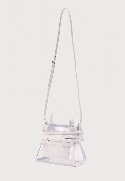 Μικρή διαφανής τσάντα χειρός με λευκή επένδυση και μακρύ ρυθμιζόμενο λουρί ώμου, παρουσιάζεται ενάντια σε απλό φωτεινό φόντο.