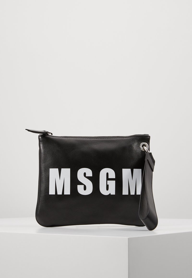 Pochette en cuir noir avec un logo MSGM blanc audacieux et une fermeture éclair, reposant sur une surface blanche contre un fond uni.