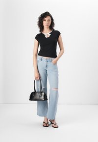 Juodas trumpomis rankovėmis viršus su balto apykakle, šviesiai mėlynos suplėšytos džinsinės kelnės, juoda odinė rankinė ir juodi šlepetės.