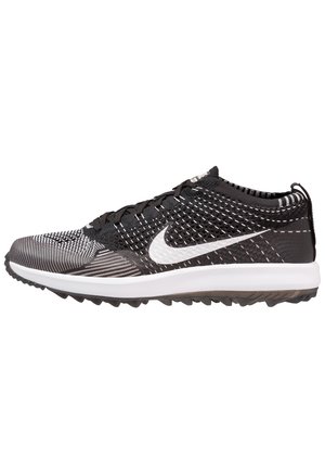 Chaussure de sport Nike noire et blanche avec une tige en mesh texturé, une semelle intermédiaire blanche rembourrée et une semelle extérieure en caoutchouc antidérapante. Talon renforcé et design à lacets.