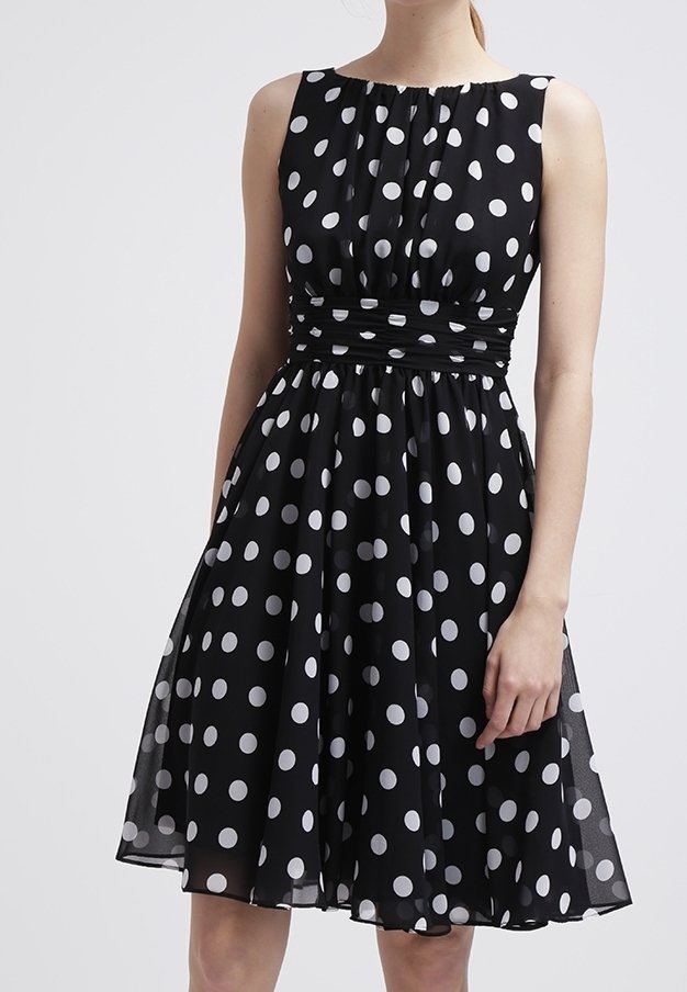 Robe noire sans manches avec des pois blancs, dotée d'un corsage ajusté et d'une jupe évasée, fabriquée en tissu léger avec une taille froncée.