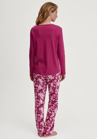 Langsleeve roze top gecombineerd met roze broek met bloemenpatroon. De stof is zacht en heeft een ontspannen pasvorm, met een ronde halslijn en lange mouwen.