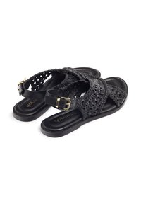 Sandali intrecciati neri con design a tracolla incrociata, suola piatta, dettaglio della fibbia dorata e soletta in pelle liscia. Materiale durevole e traspirante.