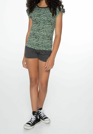 Haut vert à manches courtes avec un motif abstrait noir, assorti à un short gris et des baskets montantes noires. Tissu lisse, coupe décontractée.