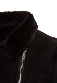 Svart faux fur-jacka som har en mjuk sammetstextur, en krage och en metalldragkedja fram.