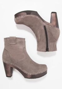 Gray suede ankle boots with a wooden block heel, featuring a side zipper, decorative studs, and a clean, rounded toe design.