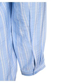 Vaalea sininen raidallinen paita, jossa on valkoisia pystysuoria viivoja, napitettavalla hihalla ja sivuaukolla. Kangas näyttää hieman ryppyiseltä.