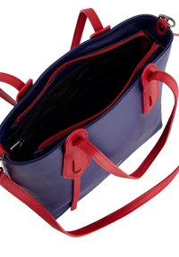 Synthetisch leren handtas met een blauwe buitenkant en rode accenten, dubbele handvatten en een ritsafsluiting. De binnenkant heeft een donkere voering met meerdere vakken.