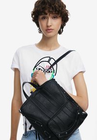 Schwarze Lederhandtasche mit strukturiertem Design, strukturierten Oberflächen und Details aus silbernem Metall. Verfügt über einen einzigen Schulterriemen und zwei Tragegriffe.