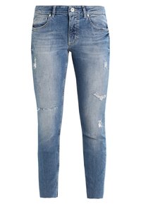 Jeans skinny de denim azul claro con un patrón desgastado, que presentan desgarros en la parte frontal, un cierre de botón y cremallera, y bolsillos tradicionales.