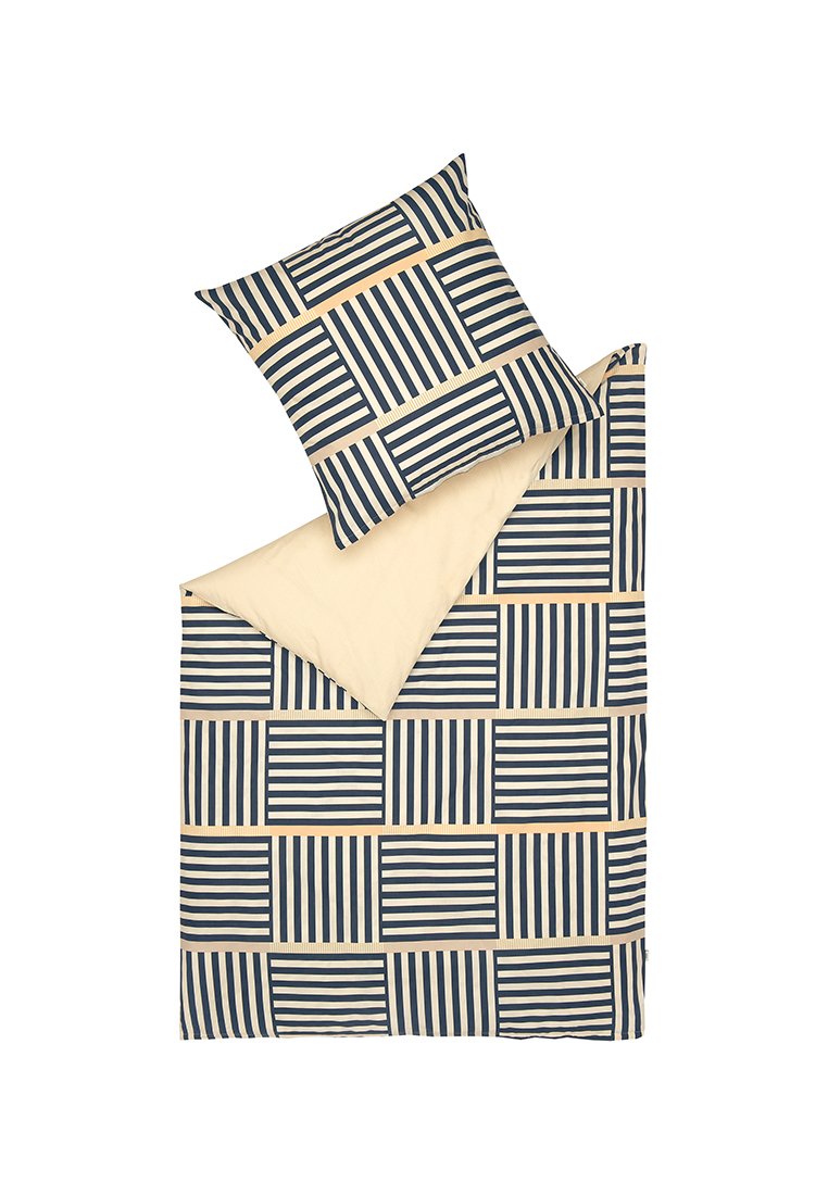 Le jeu de housse de couette et de taie d'oreiller présente un motif rayé bleu marine et crème avec un revers uni en crème, fabriqué à partir d'un tissu en coton doux.