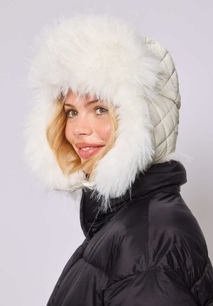 Witte nepbonten capuchon op een gewatteerde, crèmekleurige jas, aangevuld met een zwarte onderzijde. Kenmerkt zich door een gladde textuur en een fluffy ontwerp.