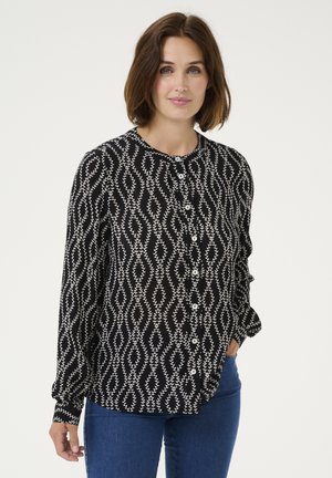 Černá button-up blůza s bílým listovým vzorem, dlouhými rukávy se nařasenými manžetami a kulatým výstřihem. Hladká textura látky.