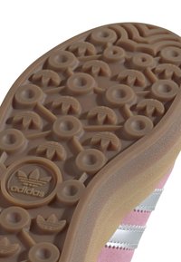 Skosål med cirkulært slidmønster, Adidas-logo og pink overdel med hvide striber synlige på siden.