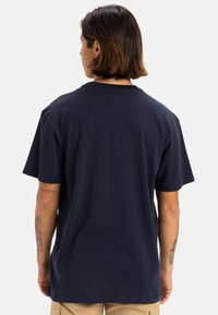 Camiseta de algodón azul marino, de mangas cortas, corte estándar, cuello redondo, textura suave, sin patrones ni gráficos visibles en la parte posterior.