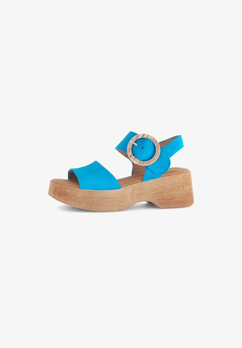 Blue platform sandals with a wooden block heel, featuring a wide strap and a circular wooden accent on the ankle strap. Smooth texture.