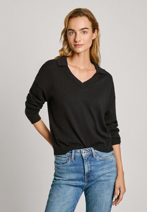 Black V-neck sweater made of soft fabric, featuring a collar and long sleeves. Paired with light blue denim jeans.