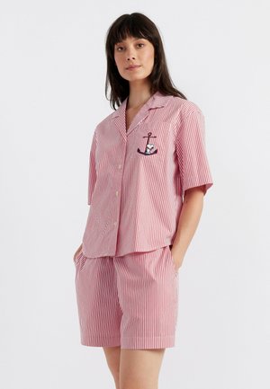 Ensemble de pyjama court rayé rouge et blanc avec une chemise à col, manches courtes, poche avant et détail brodé d'une ancre sur la poche.