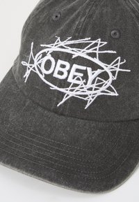 Sorte denim caps med hvit brodert "OBEY"-logo omgitt av et stjerneskudd-design. Justerbar stropp bak. Teksturert stoff.