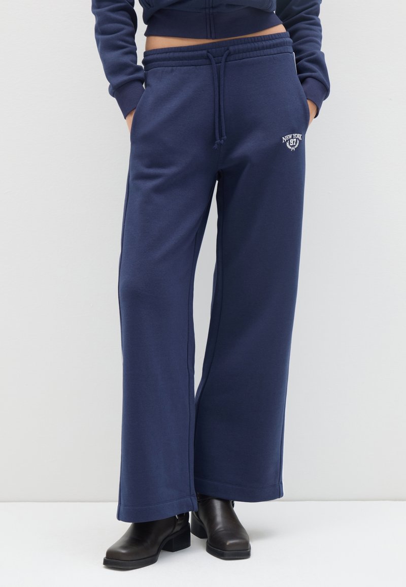 Navyblauwe wijde sweatpants gemaakt van zachte stof, met een elastische tailleband en trekkoord en een geborduurd logo "New York 97".