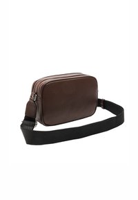 Brązowa skórzana torba na ramię z teksturowaną powierzchnią, prostokątnym kształtem, podwójnym zamkiem błyskawicznym oraz regulowanym czarnym paskiem z tkaniny.