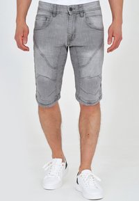 Shorts en denim gris au design ajusté, avec des motifs de couture uniques et cinq poches. Associés à des baskets blanches pour le contraste.