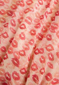 Tessuto rosa trasparente con stampe di baci di rossetto rossi e corallo e sottili righe verticali metalliche dorate.